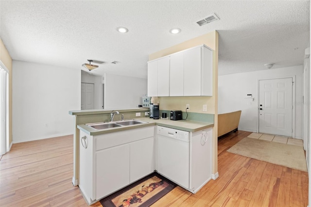 kitchen with a peninsula, visible vents, light countertops, dishwasher, and light wood finished floors