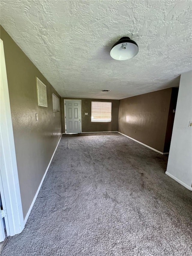 unfurnished room with a textured ceiling and carpet floors