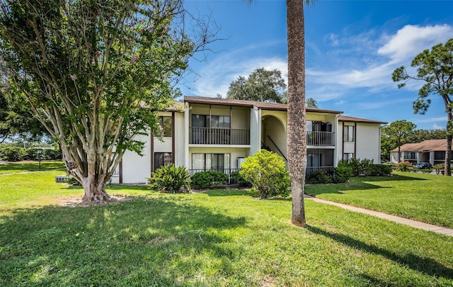 view of front of home featuring a balcony and a front lawn