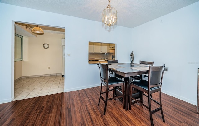 dining room featuring a textured ceiling, a notable chandelier, and hardwood / wood-style flooring