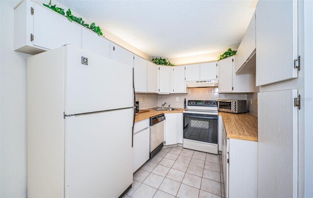 kitchen with white appliances, decorative backsplash, sink, light tile patterned flooring, and white cabinetry