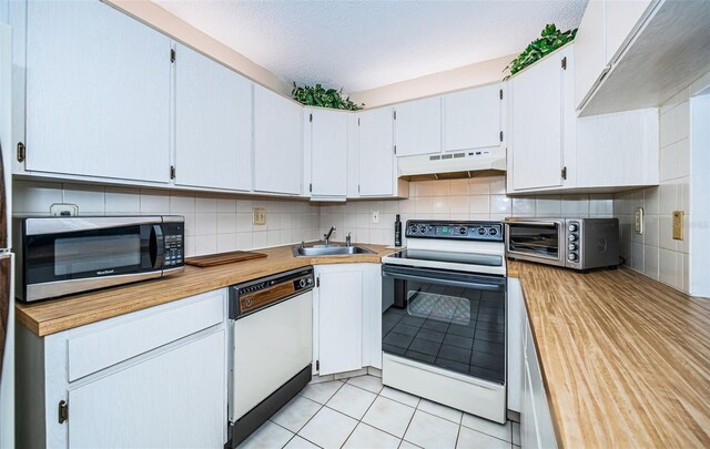 kitchen featuring white appliances, custom range hood, light tile patterned flooring, tasteful backsplash, and sink