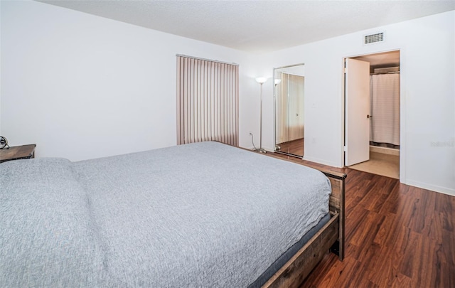 bedroom with connected bathroom and hardwood / wood-style flooring