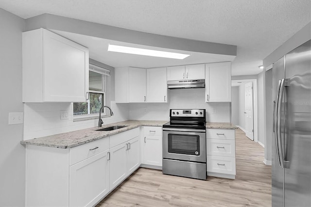 kitchen featuring under cabinet range hood, white cabinetry, appliances with stainless steel finishes, and a sink