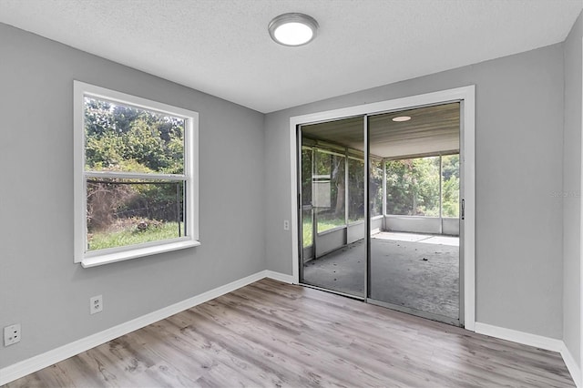 unfurnished room featuring light hardwood / wood-style flooring and a textured ceiling