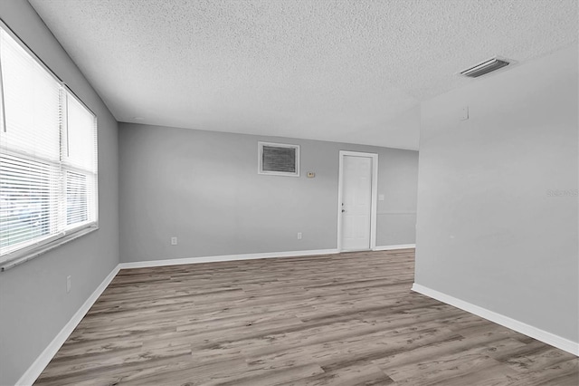 unfurnished room with a textured ceiling and hardwood / wood-style floors