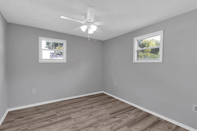 unfurnished room featuring ceiling fan, a wealth of natural light, and hardwood / wood-style floors