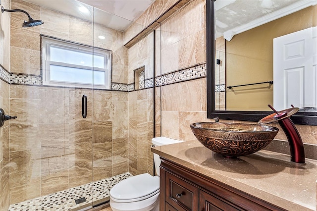 bathroom featuring toilet, crown molding, tile walls, vanity, and a shower with door