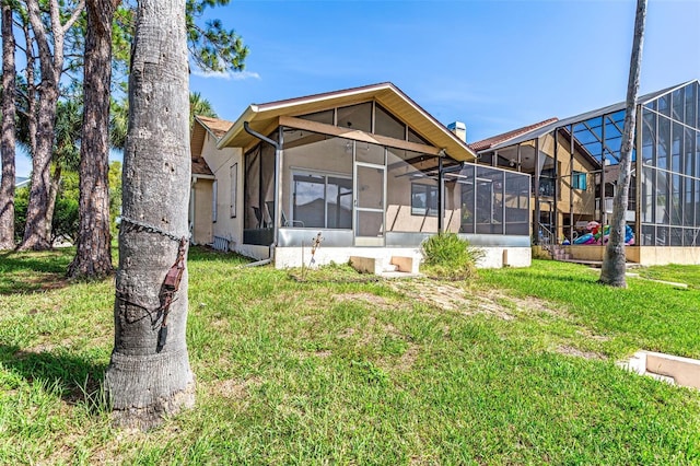 rear view of property featuring a lanai and a lawn