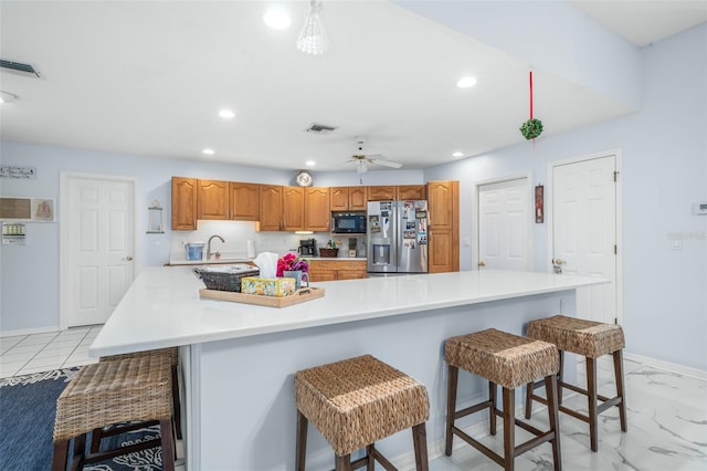 kitchen featuring ceiling fan, a large island, stainless steel fridge, and a breakfast bar