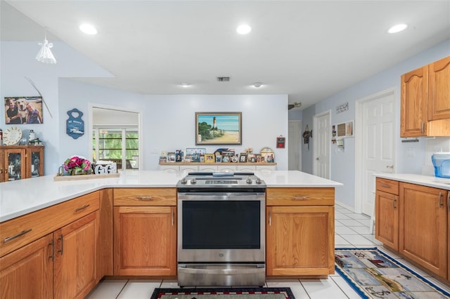 kitchen with light tile patterned flooring, stainless steel electric range, and decorative light fixtures