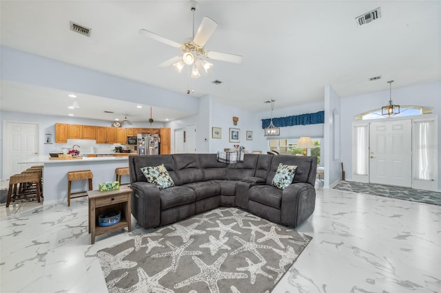 living room with ceiling fan with notable chandelier