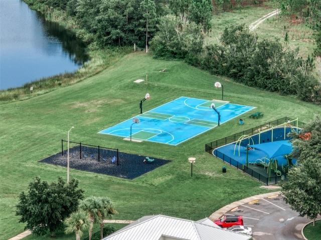 view of sport court with a lawn and a water view