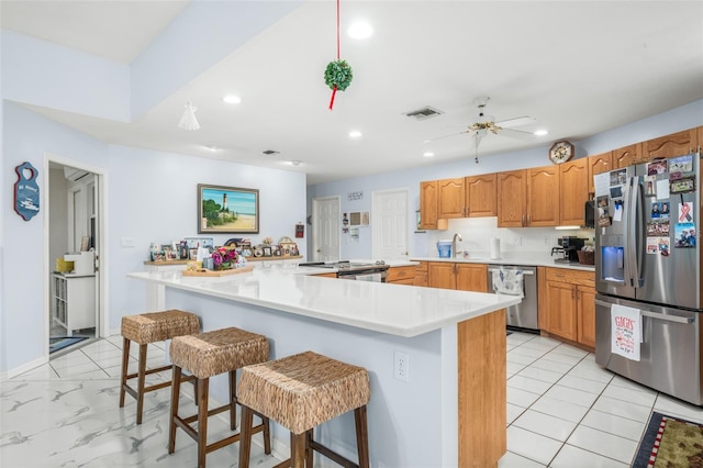 kitchen with kitchen peninsula, stainless steel appliances, a breakfast bar area, and ceiling fan