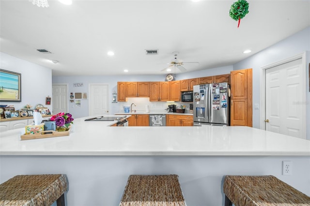 kitchen with sink, a breakfast bar, kitchen peninsula, appliances with stainless steel finishes, and ceiling fan