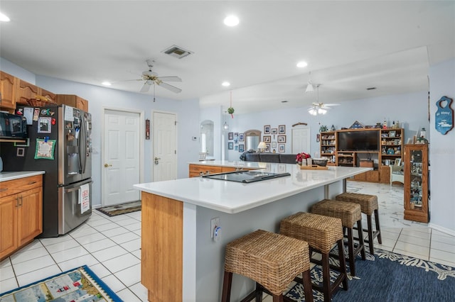 kitchen with black appliances, light tile patterned floors, a center island, and a breakfast bar