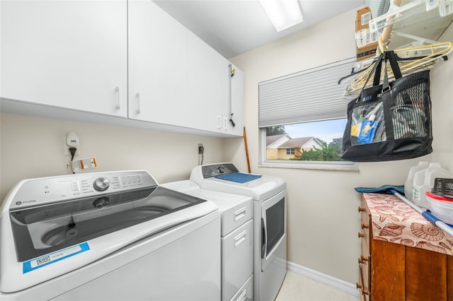 clothes washing area with washer and clothes dryer and cabinets