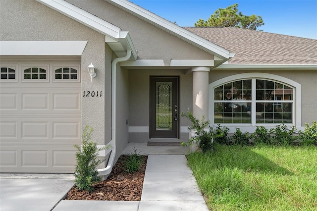 doorway to property featuring roof with shingles, an attached garage, and stucco siding