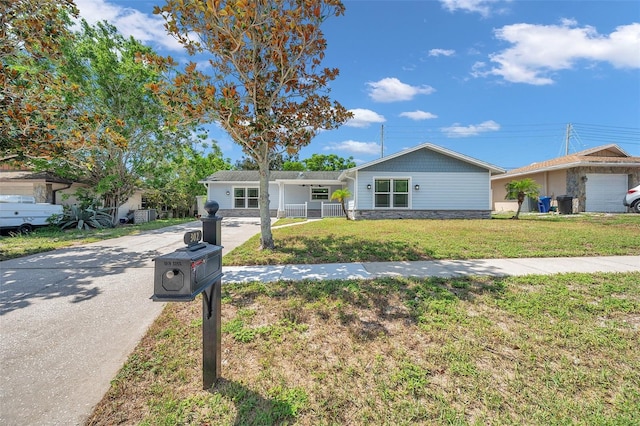 single story home featuring concrete driveway, stone siding, and a front yard