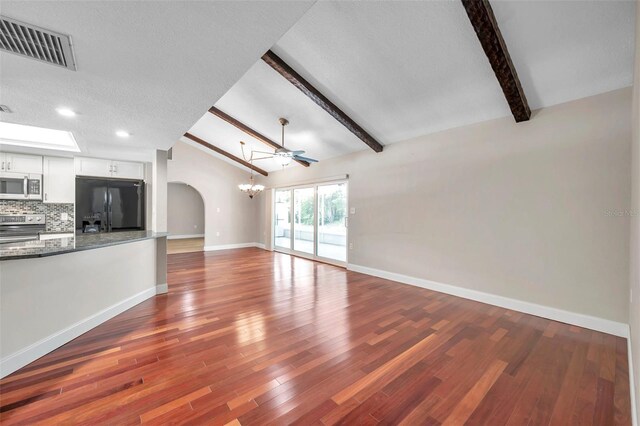 unfurnished living room featuring ceiling fan, wood-type flooring, a textured ceiling, and lofted ceiling with beams