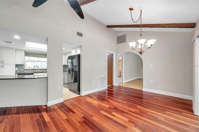 unfurnished dining area featuring beam ceiling, light hardwood / wood-style flooring, high vaulted ceiling, and ceiling fan with notable chandelier