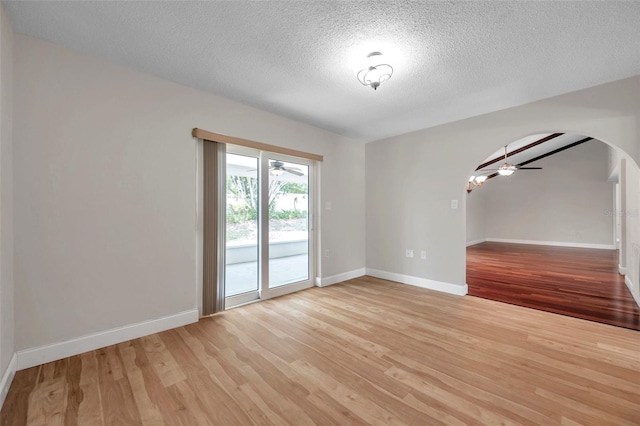 unfurnished room featuring light wood finished floors, baseboards, and arched walkways