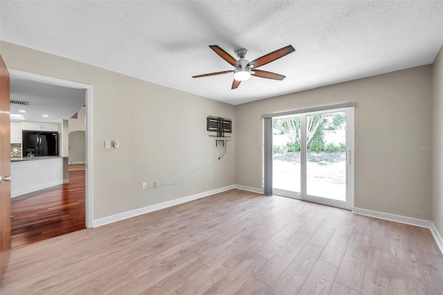 spare room with light wood-style floors, ceiling fan, and baseboards