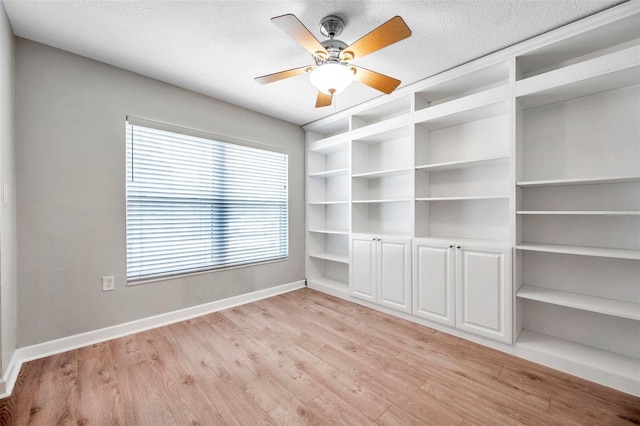 spare room with light wood-style floors, a textured ceiling, baseboards, and a ceiling fan