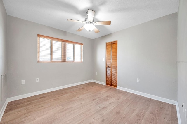 spare room featuring a ceiling fan, baseboards, a textured ceiling, and light wood finished floors