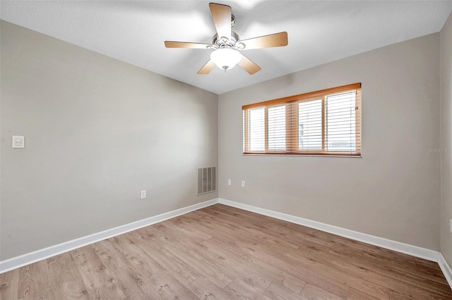 unfurnished room with ceiling fan, light wood-style floors, visible vents, and baseboards