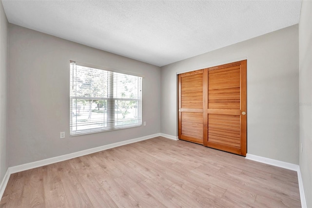 unfurnished bedroom featuring a textured ceiling, a closet, and light hardwood / wood-style floors