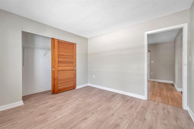 unfurnished bedroom with a closet, baseboards, a textured ceiling, and light wood finished floors