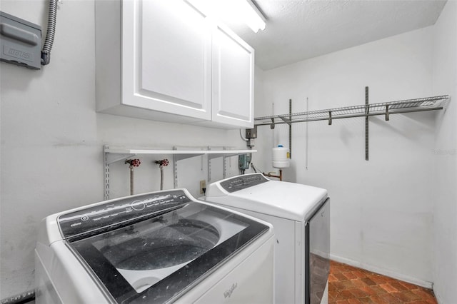 washroom featuring a textured ceiling, tile patterned floors, washing machine and clothes dryer, and cabinets