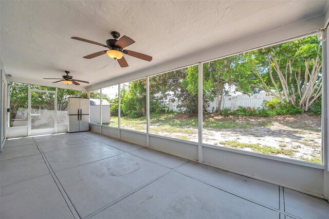 unfurnished sunroom featuring ceiling fan and a wealth of natural light