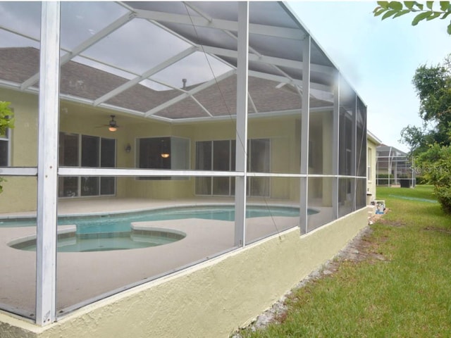 view of pool with ceiling fan, a lanai, and a lawn