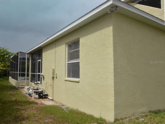 view of side of home with a lanai and a lawn