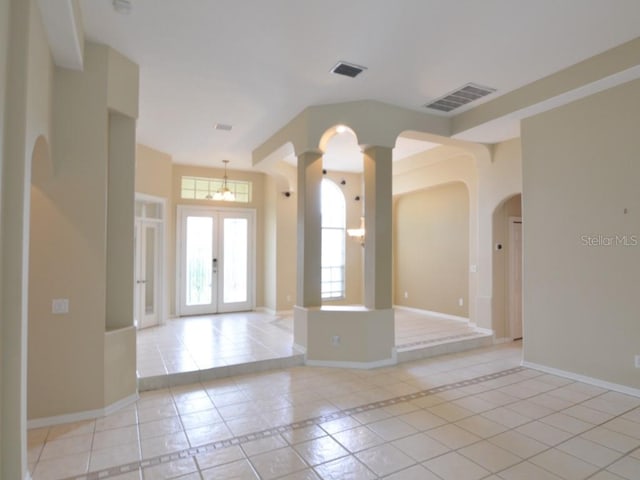 unfurnished room featuring ornate columns, light tile patterned flooring, and french doors