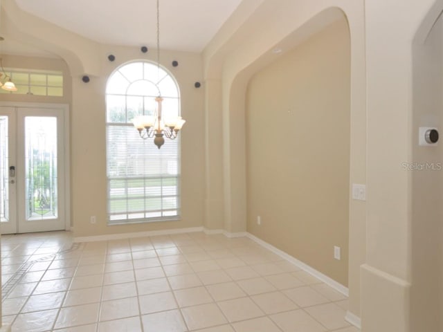 spare room featuring light tile patterned flooring, a healthy amount of sunlight, and french doors