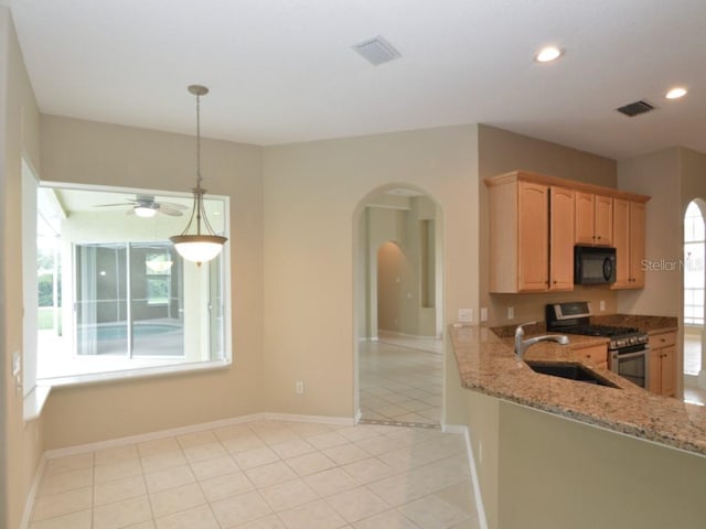 kitchen featuring light tile patterned flooring, stainless steel range with gas cooktop, decorative light fixtures, sink, and light stone counters