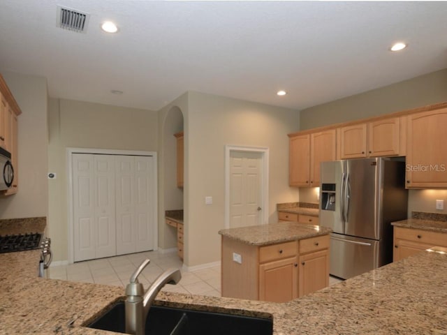 kitchen with light brown cabinetry, sink, light tile patterned floors, and stainless steel fridge