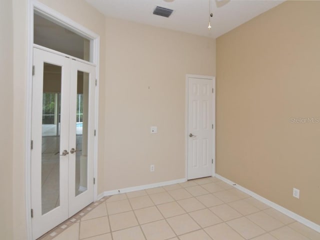 tiled empty room featuring ceiling fan and french doors