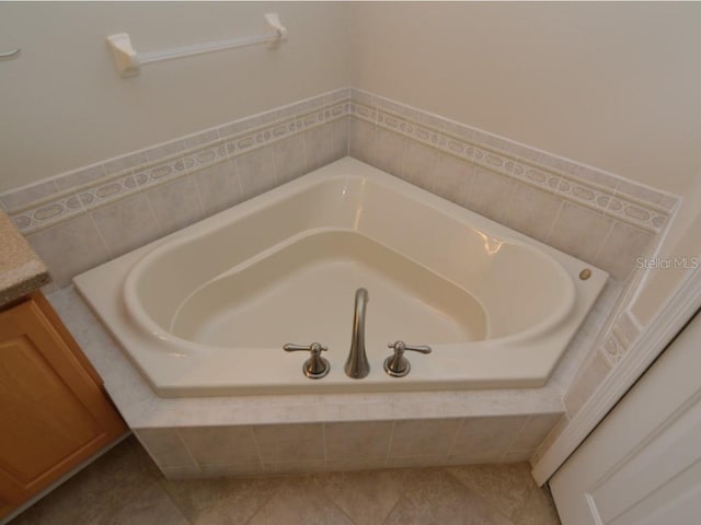 bathroom featuring vanity, tiled tub, and tile patterned flooring