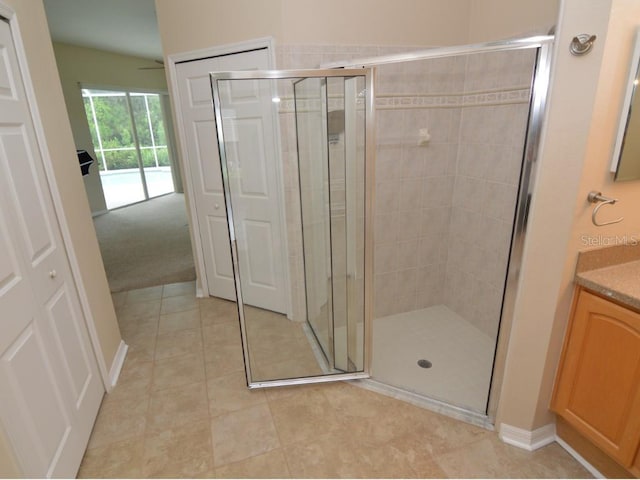 bathroom featuring a shower with door, vanity, and tile patterned floors