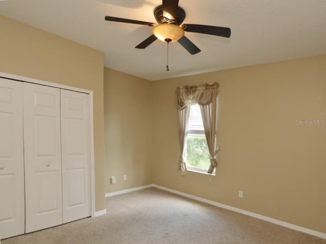 unfurnished bedroom featuring ceiling fan, a closet, and light carpet