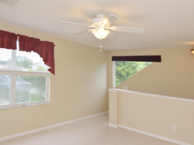 empty room with plenty of natural light, light carpet, and ceiling fan