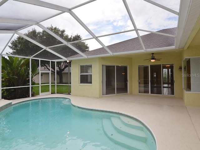 view of swimming pool featuring a patio, ceiling fan, and glass enclosure