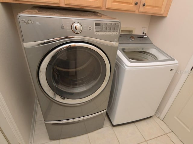 washroom featuring cabinets, independent washer and dryer, and light tile patterned flooring