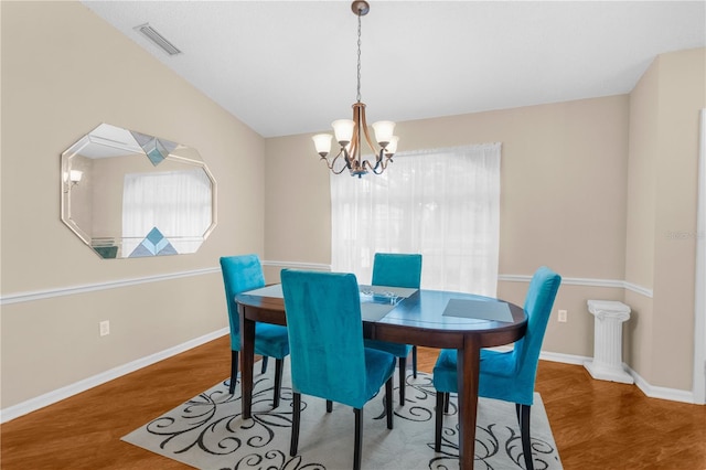 dining room with a notable chandelier, vaulted ceiling, and wood-type flooring