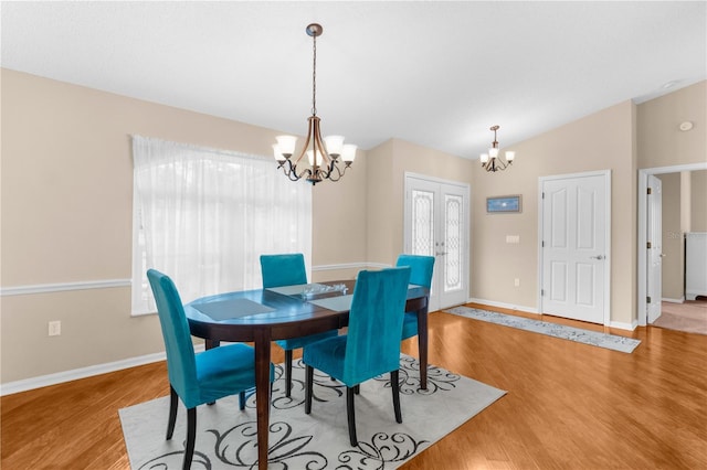 dining area featuring light hardwood / wood-style flooring, lofted ceiling, and a notable chandelier