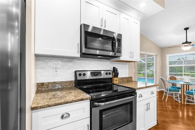 kitchen with ceiling fan, dark wood-type flooring, white cabinets, lofted ceiling, and stainless steel appliances